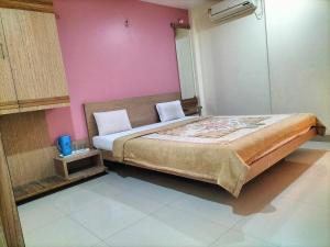 1 dormitorio con 1 cama grande y pared de color rosa en HOTEL SAI SURYA en Shirdi