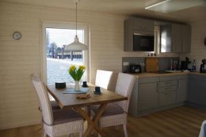 a kitchen with a wooden table and chairs and a table and a window at Hausboot Liliput in Stralsund