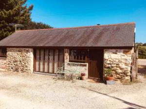 a small stone building with a brown roof at Cozy, open plan barn with log burner in Truro