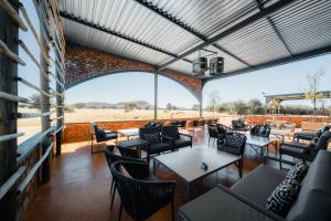 un restaurant avec des tables et des chaises et une grande fenêtre dans l'établissement Okonjima Plains Camp, à Otjiwarongo