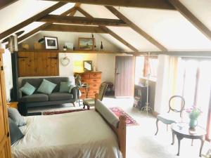a living room with a bed and a couch at Cozy, open plan barn with log burner in Truro