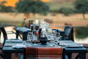 a table with wine glasses and bottles on it at Okonjima Luxury Bush Camp in Otjiwarongo