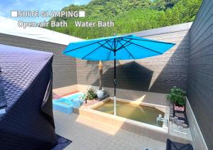 ein Badewasser-Bad im Freien mit einem Sonnenschirm in der Unterkunft Bihadanoyu Koshikano Onsen in Kirishima