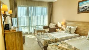 una camera d'albergo con due letti e una sedia di DIT Evrika Beach Club Hotel - All Inclusive a Sunny Beach