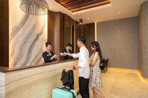 a man and a woman standing in a lobby with luggage at Wiltop by BENCOOLEN in Jambi