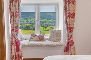 asiento junto a la ventana con almohadas en Sun Cottage with stunning lake views, Coniston en Coniston