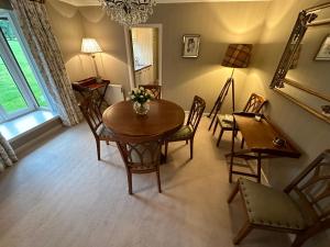 uma sala de jantar com uma mesa, cadeiras e um espelho em One Dunbar Court Gleneagles Village em Auchterarder