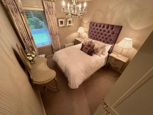 a small bedroom with a bed and a chandelier at One Dunbar Court Gleneagles Village in Auchterarder