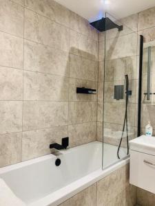 ein Bad mit einer Dusche, einer Badewanne und einem Waschbecken in der Unterkunft One bedroom posh and neat flat in Thamesmead