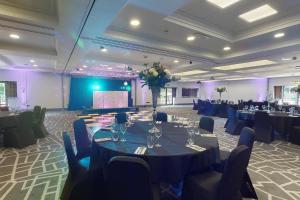 a banquet hall with tables and chairs and a stage at Village Hotel Leeds North in Leeds