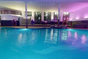 a large swimming pool with blue water in a building at Village Hotel Leeds North in Leeds