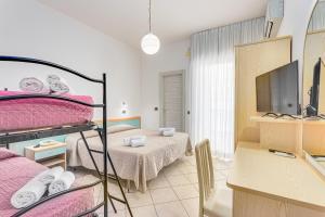 a bedroom with a bunk bed and a desk with a television at Hotel Costaverde in Cesenatico