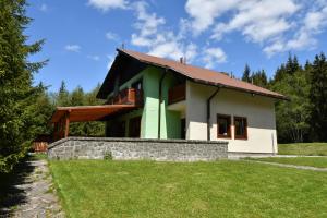 uma casa verde e branca com uma parede de pedra em Poľovnícka chata Štefana em Mlynky 