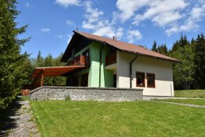 a green and white house with a stone wall at Poľovnícka chata Štefana in Mlynky 