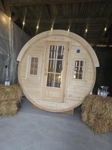 a large wooden circle with two windows and hay bales at Schlaffass mit Wellness in alter Scheune in Seinsheim