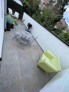 a patio with a table and chairs and a white wall at Charmant appartement au look design in Mons