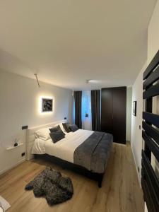 a bedroom with a large bed and a wooden floor at Charmant appartement au look design in Mons