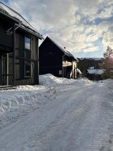 a snow covered road next to a building with snow at Vasabyn Fjällbacken - Lindvallen - Ski in Ski out in Sälen