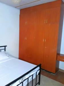 a bedroom with a bed and a wooden cabinet at New Kitisuru A in Nairobi