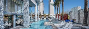 a hotel swimming pool with chairs and palm trees at Modern Luxury 17 Floor Panoramic Huge Corner Suite in Las Vegas