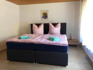 Schlafzimmer mit einem Bett mit rosa Bettwäsche und rosa Kissen in der Unterkunft Haus Ahkamp in Hemmoor