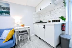a white kitchen with a desk and a blue chair at Cozy Studio retreat in Vibrant Crystal Palace, in Upper Norwood +2 photos