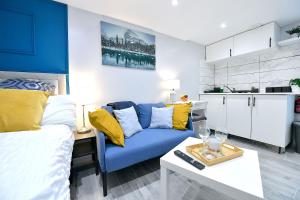 a living room with a blue couch and a kitchen at Cozy Studio retreat in Vibrant Crystal Palace, in Upper Norwood