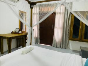 een slaapkamer met een wit bed en een raam bij Rams Resort in Arugam Bay