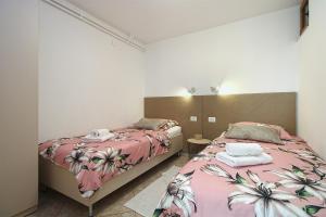 - une chambre avec 2 lits avec des draps roses dans l'établissement Apartments Slavko 1179, à Banjole