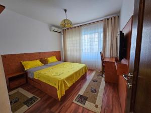 a bedroom with a yellow bed and a television at Cosy apartment close to City Center with parking lot in Bucharest