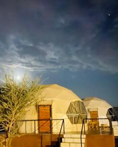 two domed tents in a field under a cloudy sky at Bilal luxury camp in Wadi Rum