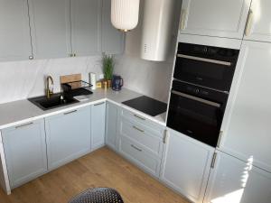 a kitchen with white cabinets and a black stove top oven at Apartament Mazovia Prestige in Płock