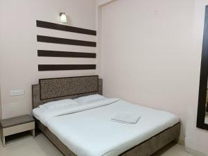 a white bed with a black and white striped wall at Hotel Satyam in Jaigaon