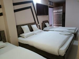 two beds in a room with white sheets and pillows at Hotel Satyam in Jaigaon