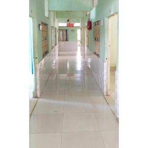 um corredor vazio num hospital com piso de azulejo branco em Hotel HillView, Junagadh em Junagadh