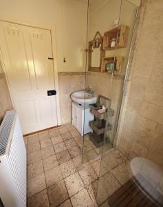 y baño con ducha, aseo y lavamanos. en Teach Róisin-Traditional Irish holiday cottage in Malin Head. en Malin