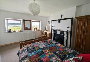 a bedroom with a bed with a quilt on it at Teach Róisin-Traditional Irish holiday cottage in Malin Head. in Malin