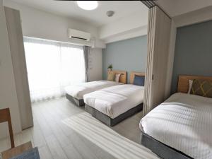 a bedroom with two beds and a window at ESLEAD HOTEL Namba Daikokucho in Osaka