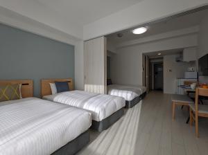 a hotel room with three beds and a table at ESLEAD HOTEL Namba Daikokucho in Osaka
