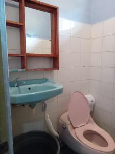 a bathroom with a toilet and a sink and a window at G - RIMA GARDEN HomeStay in Lengkoajang