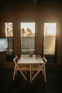 a table and chairs in a room with two windows at Nydelig moderne hytte på Geilo Kikut med høy standard - 4 senger 6 gjester in Geilo