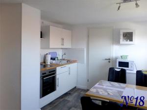 a kitchen with white cabinets and a table and a microwave at Ferienwohnung Gerhards in Esens