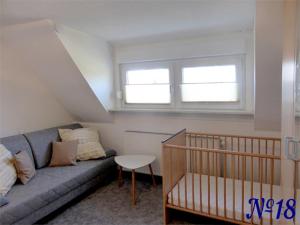 ein kleines Wohnzimmer mit einem Sofa und einem Kinderbett in der Unterkunft Ferienwohnung Gerhards in Esens