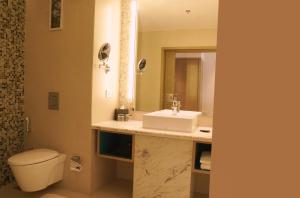 a bathroom with a sink and a toilet and a mirror at Gokulam Grand Trivandrum in Trivandrum