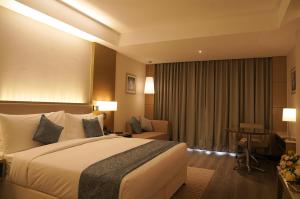 a hotel room with a large bed and a desk at Gokulam Grand Trivandrum in Trivandrum