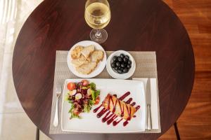 a table with a plate of food and a glass of wine at Hotel Dom Goncalo & Spa in Fátima