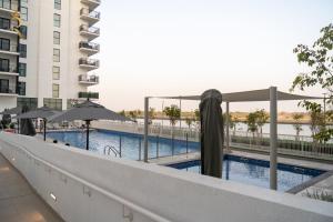 a swimming pool with umbrellas next to a building at Rodeo Retreat - Chic 1BR Apartment on Yas Island, 12 Min to Grand Prix in Abu Dhabi