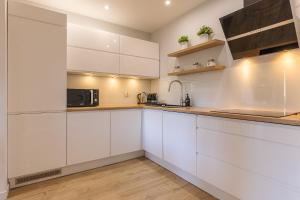 a kitchen with white cabinets and a microwave at RentPlanet - Apartament Bawaria in Szklarska Poręba