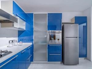 una cucina con armadi blu e frigorifero in acciaio inossidabile di Appartamento Diamante a Gorizia