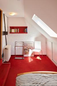 a attic room with a red carpet and a white chair at Mählich Haus in Manderscheid
